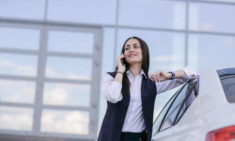 smiling woman with elbow leaning car while talking phone WingsMyPost