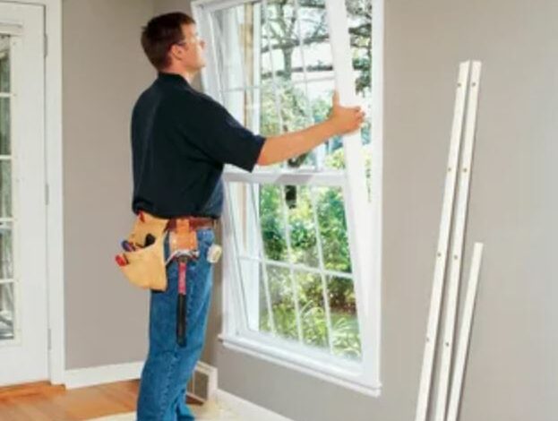 A man carefully installs a window in a residential home, ensuring a secure fit and proper alignment.